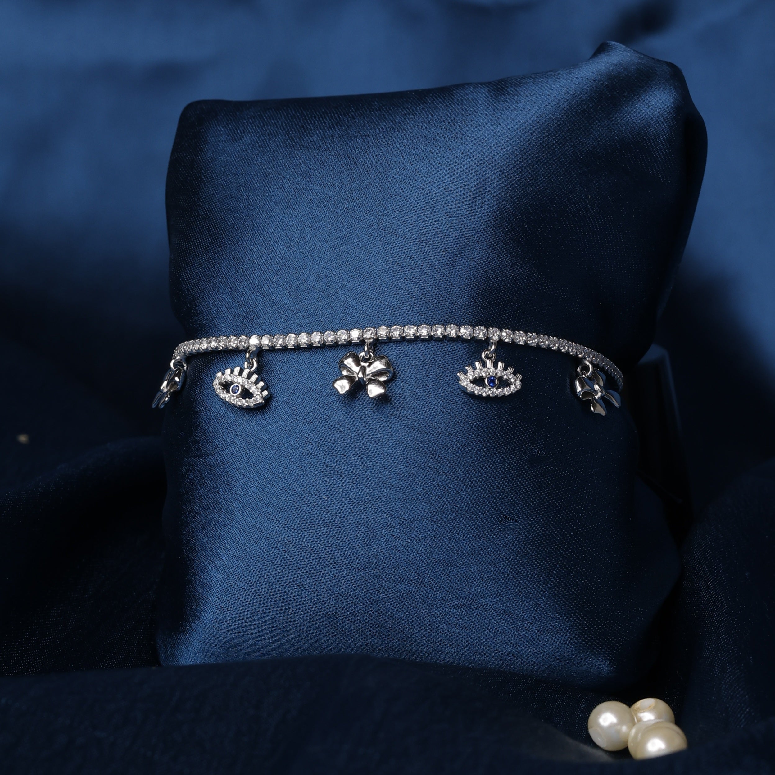 Silver bracelet with charms on a dark blue fabric background