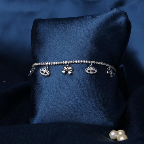 Silver bracelet with charms on a dark blue fabric background